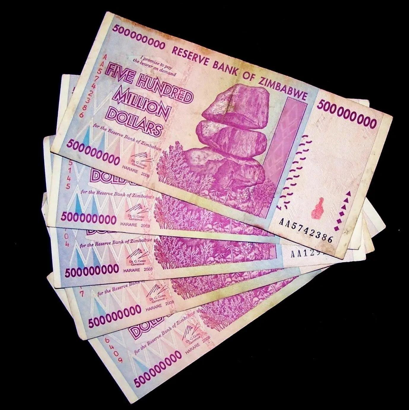Stack of Zimbabwe 500 million dollar banknotes with purple design and balancing rocks.