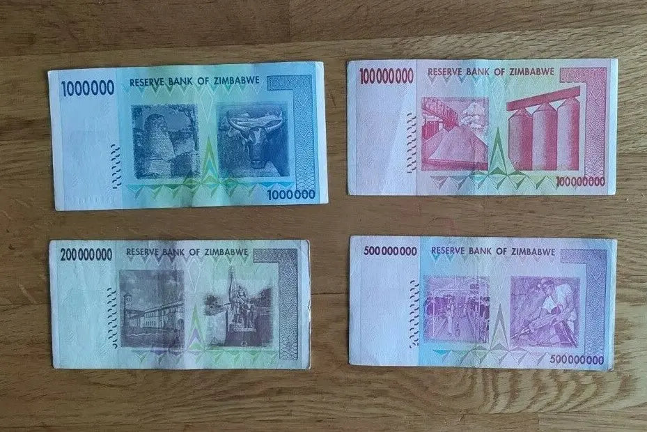 Four Zimbabwean banknotes on wood surface, displaying Reserve Bank of Zimbabwe currency