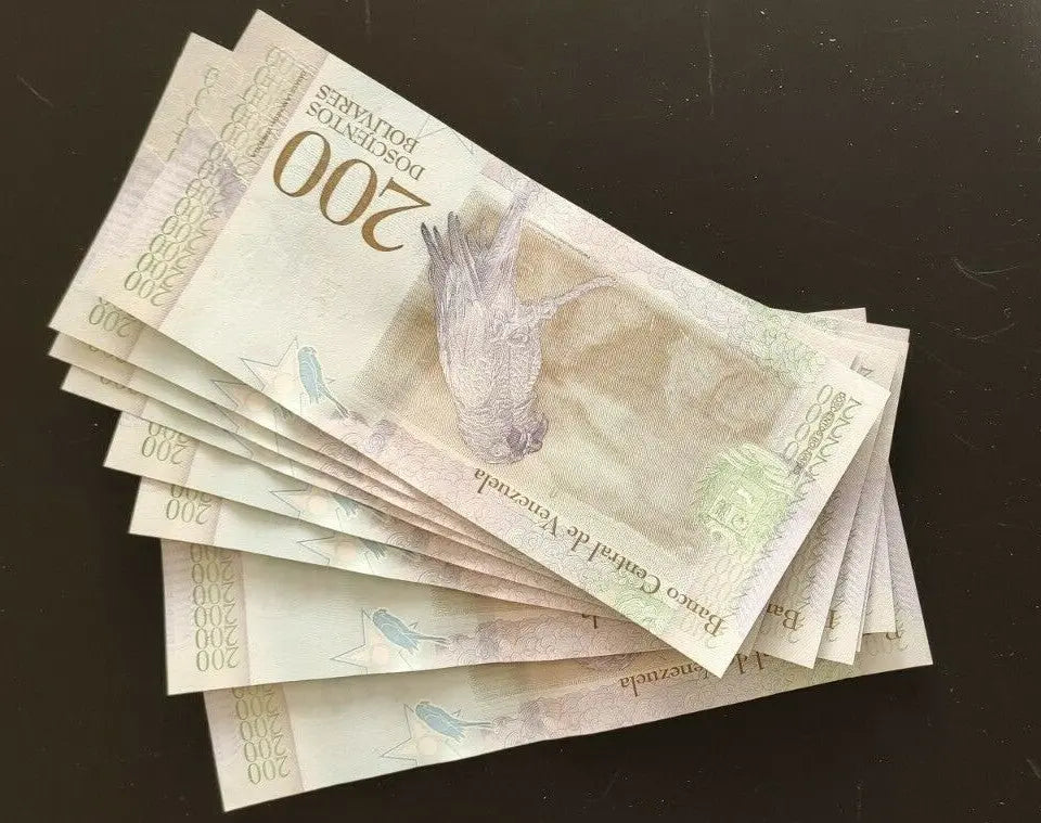Stack of 200 bolívares Venezuelan banknotes featuring bird design on dark surface