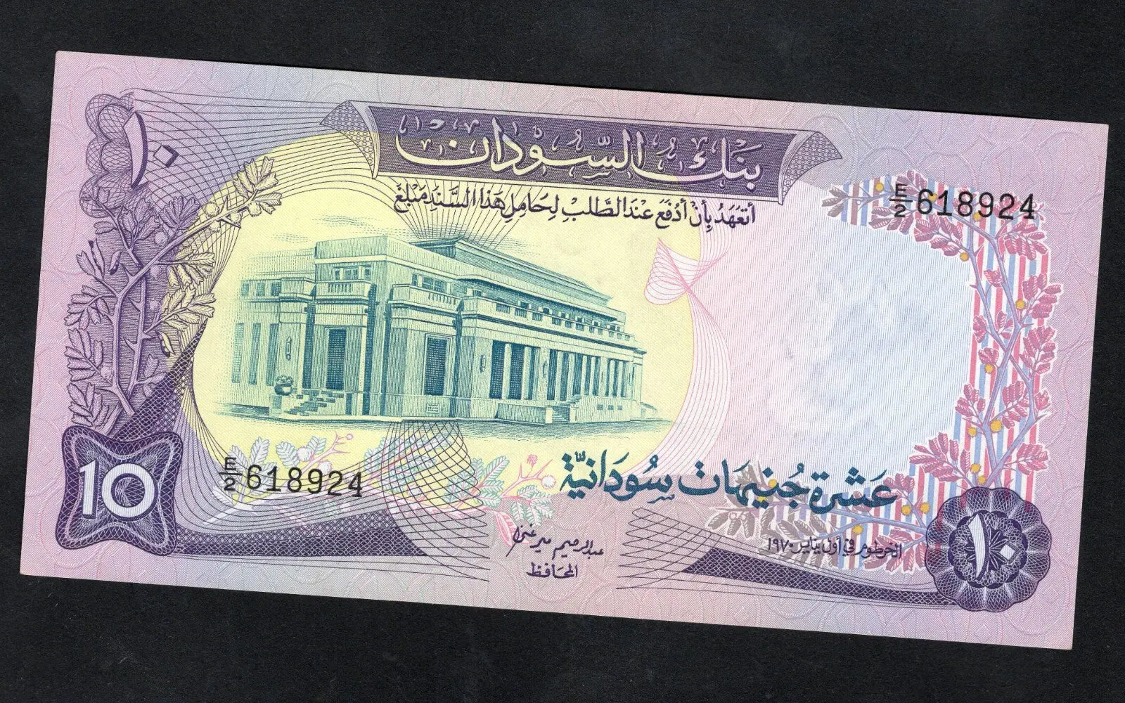 Actual photo of a 1970 Sudan 10 Pounds banknote, Pick 15a, featuring the Bank of Sudan building and Port Sudan scene in Uncirculated condition.